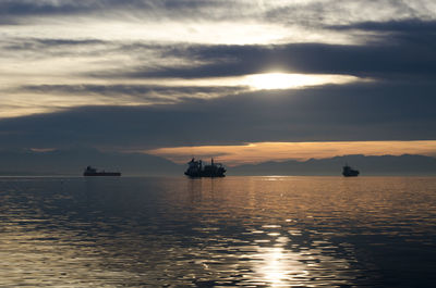 Silhouette boat sailing on sea against sky during sunset