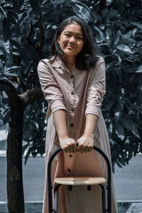 A young girl holding the back of a chair smiling to the camera 