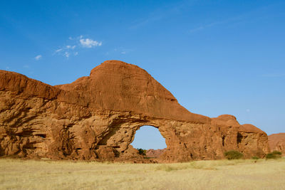 Low angle view of rock formations on landscape against blue sky