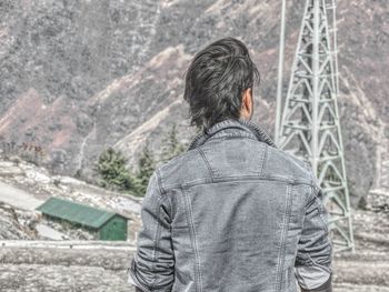 Rear view of man wearing jacket looking at mountain
