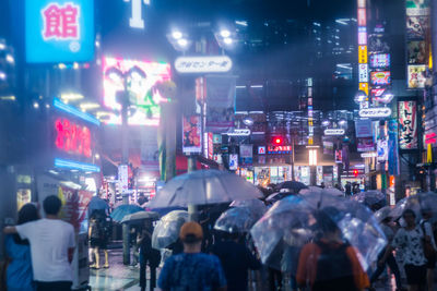 Crowd walking on illuminated city at night