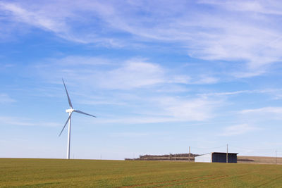 Wind turbine on field against sky