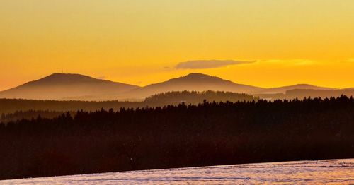 Scenic view of silhouette mountains against orange sky