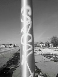 Road sign by pole against clear sky