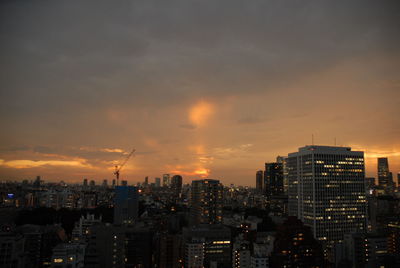 Illuminated buildings in city against sky during sunset