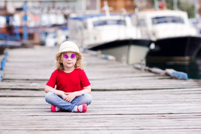 Girl with hat and sunglasses sitting on jetty