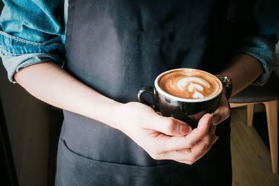 Midsection of man holding coffee at home