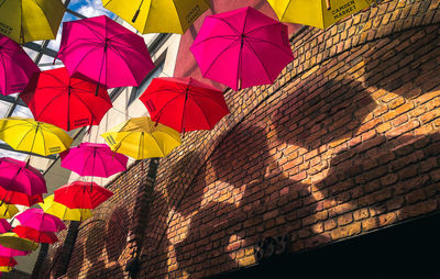 Low angle view of multi colored umbrellas hanging on shadow