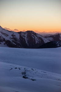 Scenic view of snow covered mountains against sky during sunset