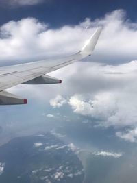 Airplane wing over clouds against sky