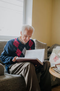 Midsection of man holding while sitting at home