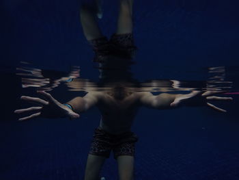 Midsection of man swimming in pool at night