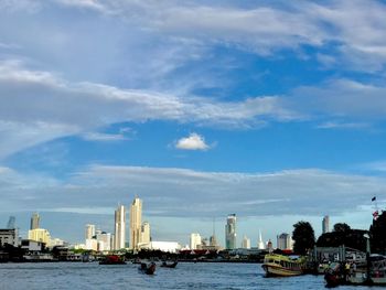 View of buildings by river against cloudy sky