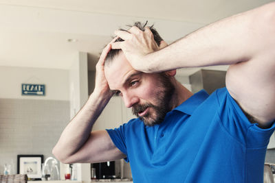 Frustrated young man with head in hands sitting at home