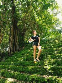 Full length of woman standing on steps against trees