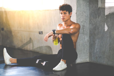 Full length portrait of man sitting in gym