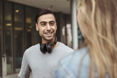 Smiling young man talking to female friend at university campus