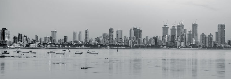 Sea and modern buildings in city against sky