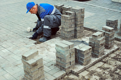 Bricklayer lays paving slabs outside. working man performs landscaping. builder lays out sidewalk