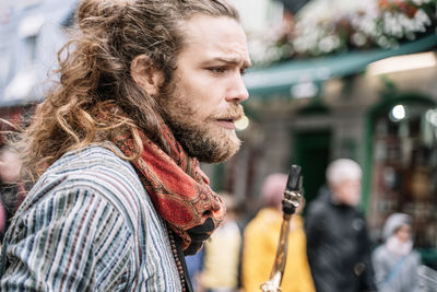Blond man with long hair and beard dressed in hippie clothes with a saxophone