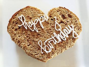 High angle view of birthday text on heart shape bread on white background