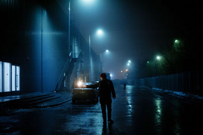 Man standing on illuminated road against sky at night