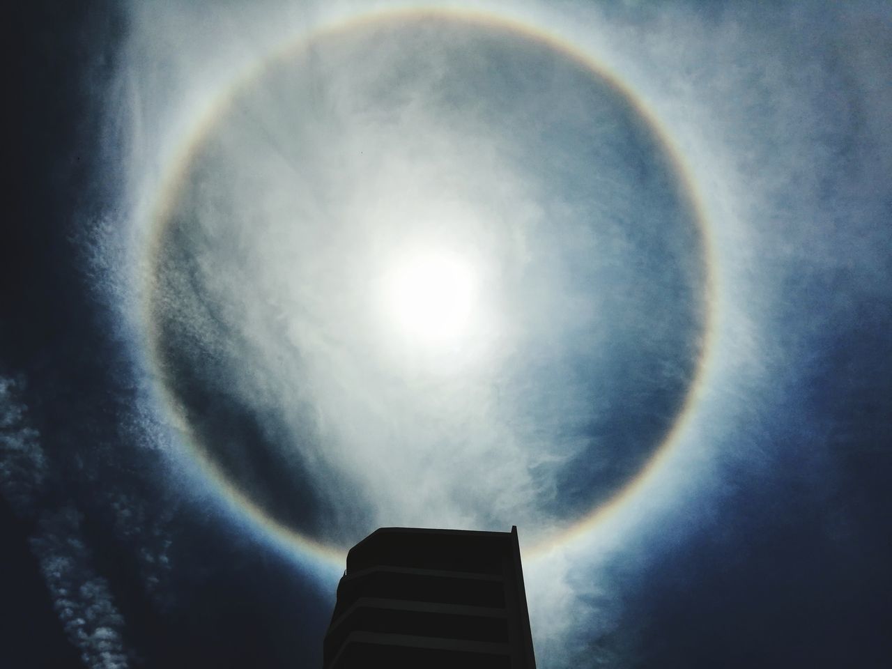 LOW ANGLE VIEW OF RAINBOW AGAINST BRIGHT SUN IN SKY