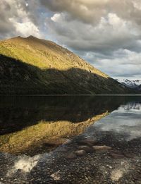 Scenic view of lake by mountain against sky