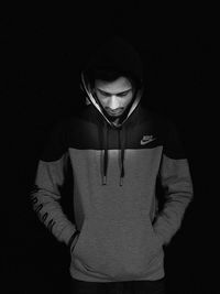 Portrait of young man standing against black background