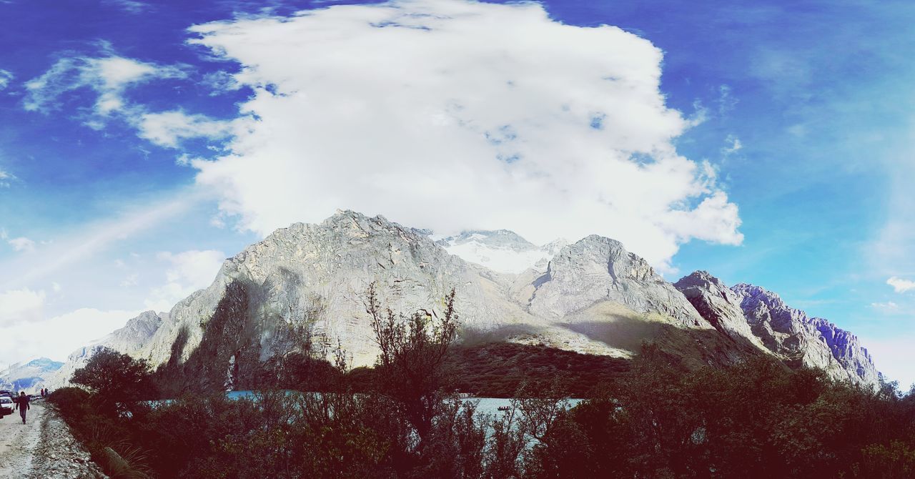 sky, low angle view, mountain, snow, cold temperature, winter, cloud - sky, tranquility, nature, cloud, blue, scenics, beauty in nature, weather, sunlight, day, tranquil scene, rock - object, tree, mountain range