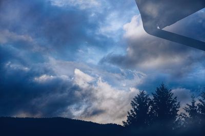 Low angle view of silhouette trees against sky