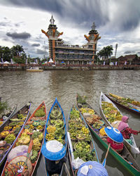 View of boats moored in lake against cloudy sky