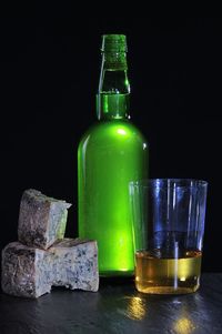 Close-up of glass bottle on table against black background