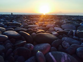 Surface level of pebbles at shore against sky during sunset