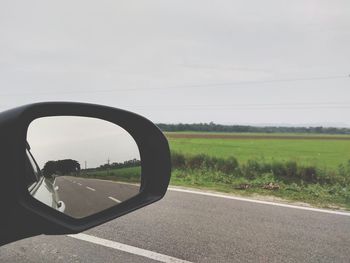 Road seen through side-view mirror of car