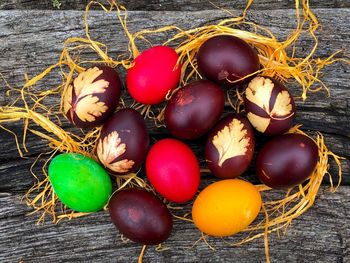 Red easter eggs decorated with leaf imprints and other colourful easter eggs on a rustic table
