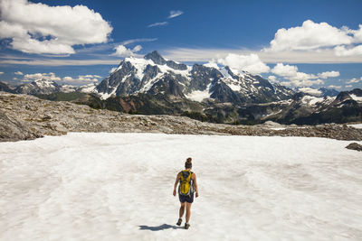 Rear view of female hiker walking on snow against mountains and cloudy sky during winter at north cascades national park