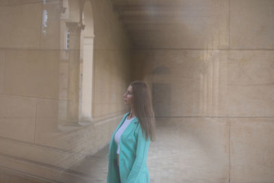 Young woman standing against wall