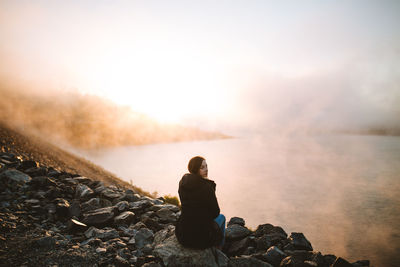 Rear view of man sitting on rock