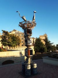 Statue in city against clear blue sky