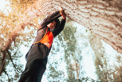 Low angle view of woman standing on tree trunk