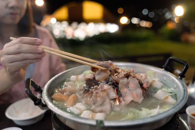 Midsection of woman holding food with chopsticks at restaurant