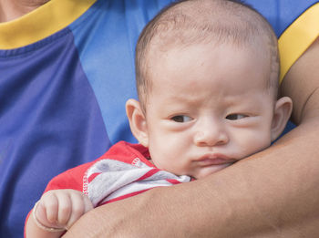 The father carried the baby, wearing a red and white striped shirt