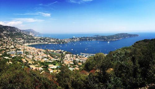 High angle view of city by sea against blue sky