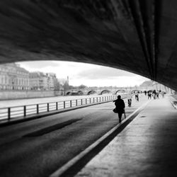 People walking on bridge in city against sky