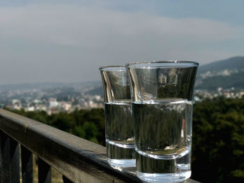 Close-up of drink in glass on railing against sky