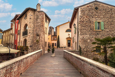 Footpath amidst buildings against sky