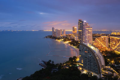 High angle view of illuminated city by sea against sky