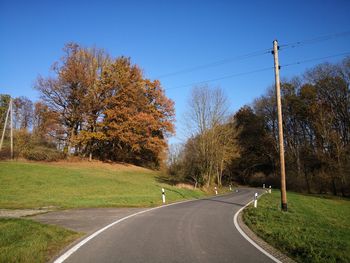 Road amidst trees against sky during autumn