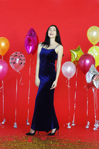 Full length of a smiling young woman with red balloons